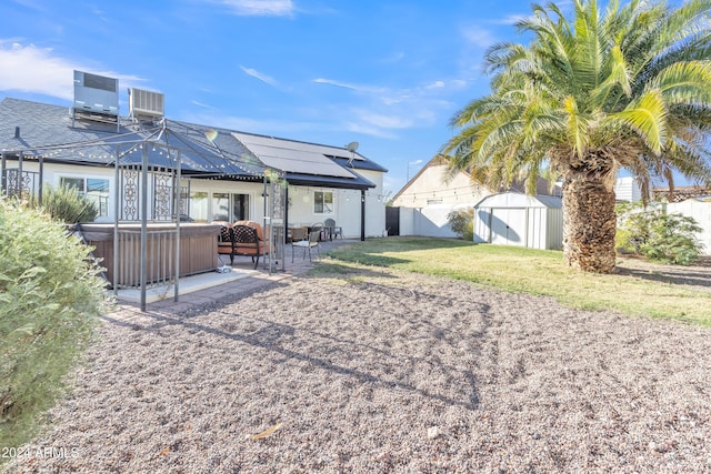 view of yard with central AC, a patio, a hot tub, and a storage shed