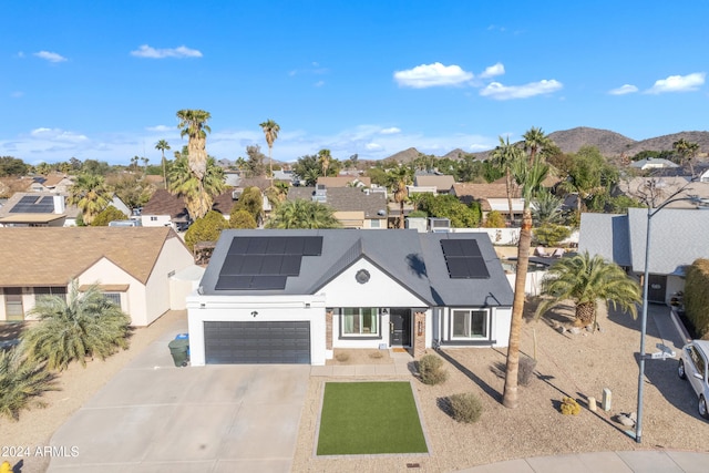 view of front of home featuring a mountain view, solar panels, and a garage