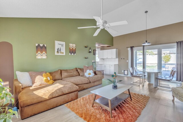 living room featuring light hardwood / wood-style flooring, high vaulted ceiling, and ceiling fan