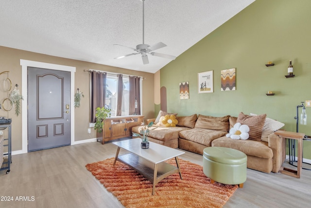 living room with ceiling fan, high vaulted ceiling, light hardwood / wood-style floors, and a textured ceiling