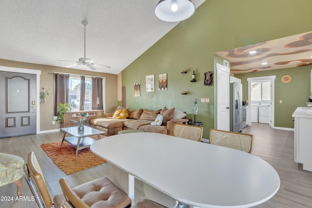 dining room featuring independent washer and dryer, light hardwood / wood-style floors, high vaulted ceiling, and plenty of natural light