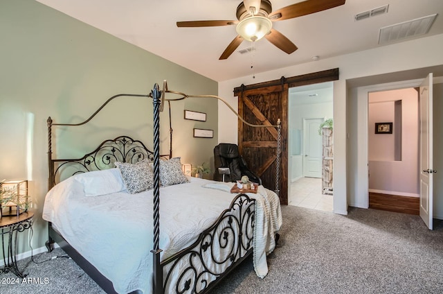 carpeted bedroom with ceiling fan and a barn door