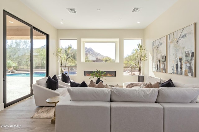 living area with light wood-type flooring, visible vents, and recessed lighting