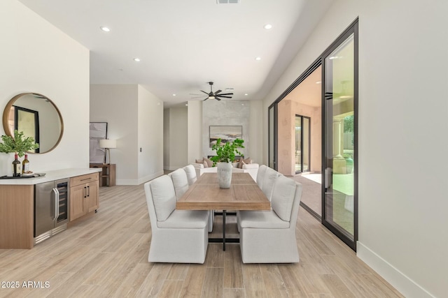 dining space featuring baseboards, wine cooler, and light wood-style floors