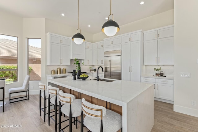 kitchen with built in refrigerator, white cabinetry, decorative backsplash, and a sink