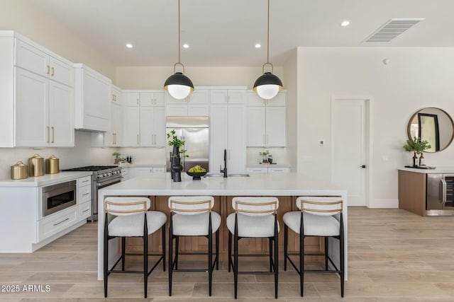 kitchen with visible vents, light countertops, a sink, and built in appliances