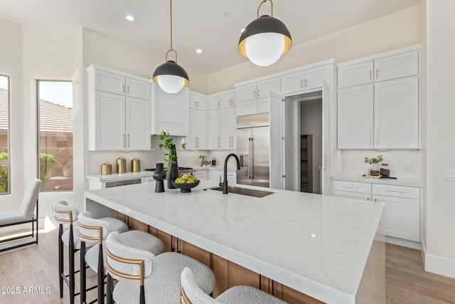 kitchen featuring white cabinets, light wood finished floors, decorative backsplash, and built in fridge