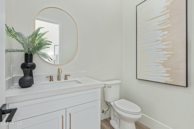 bathroom with vanity, wood finished floors, toilet, and baseboards