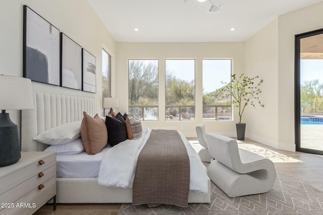 bedroom with access to outside, wood finished floors, visible vents, and multiple windows