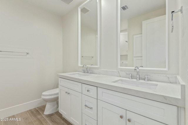 full bathroom with visible vents, a sink, toilet, and wood finished floors