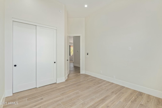 unfurnished bedroom with light wood finished floors, a closet, recessed lighting, and baseboards