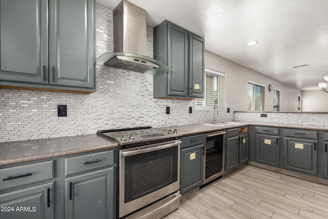 kitchen with gray cabinetry, wine cooler, backsplash, wall chimney exhaust hood, and stainless steel range with electric cooktop