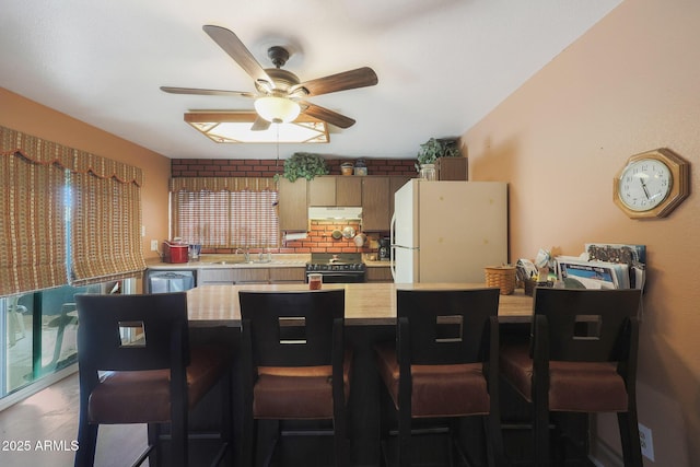 kitchen with range, a breakfast bar, sink, and white refrigerator