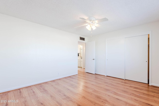 unfurnished bedroom featuring ceiling fan, a closet, a textured ceiling, and light hardwood / wood-style floors