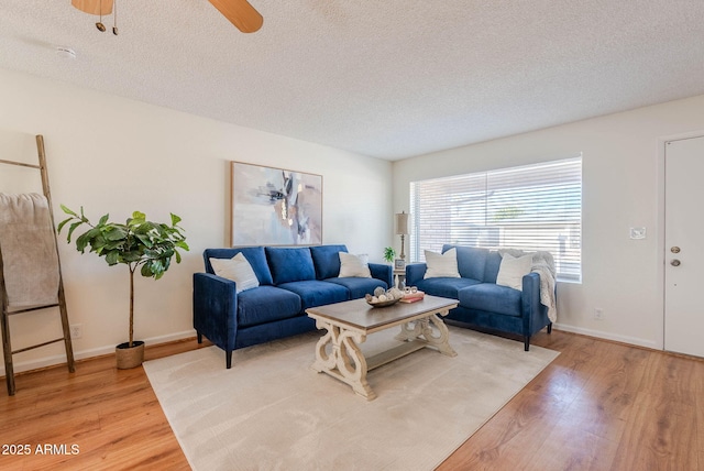 living room with ceiling fan, a textured ceiling, and light hardwood / wood-style flooring