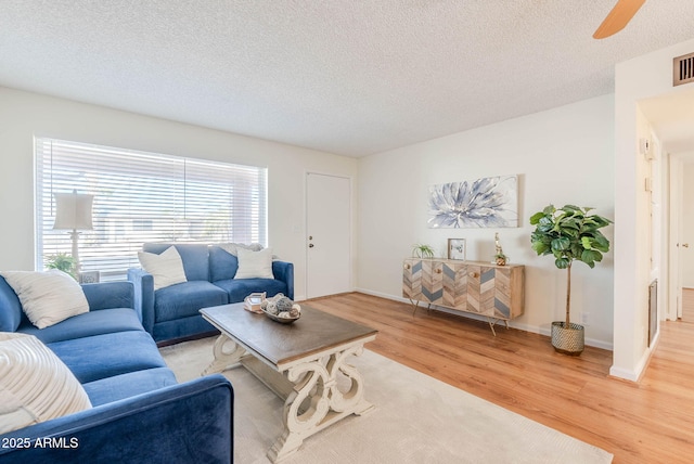 living room featuring hardwood / wood-style flooring, a textured ceiling, and ceiling fan