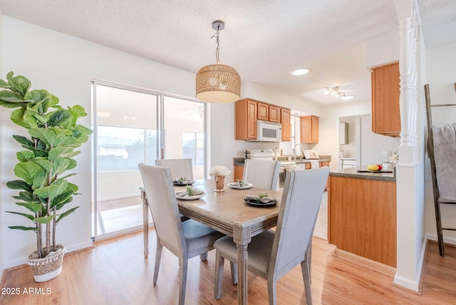 dining room with a textured ceiling, light hardwood / wood-style flooring, and sink