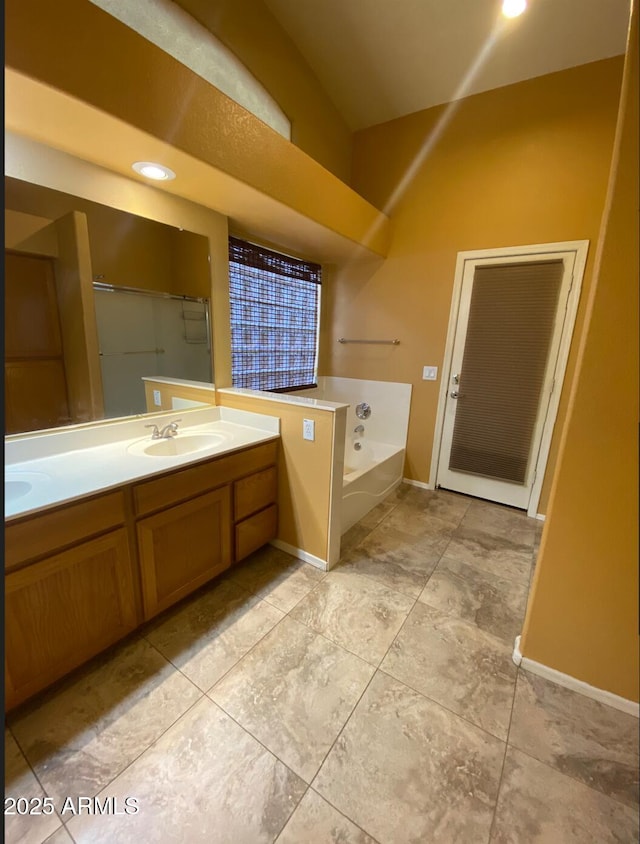 bathroom with a bath, double vanity, baseboards, and a sink