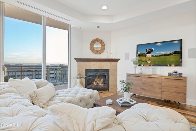 living room with a tiled fireplace, a wealth of natural light, and hardwood / wood-style flooring