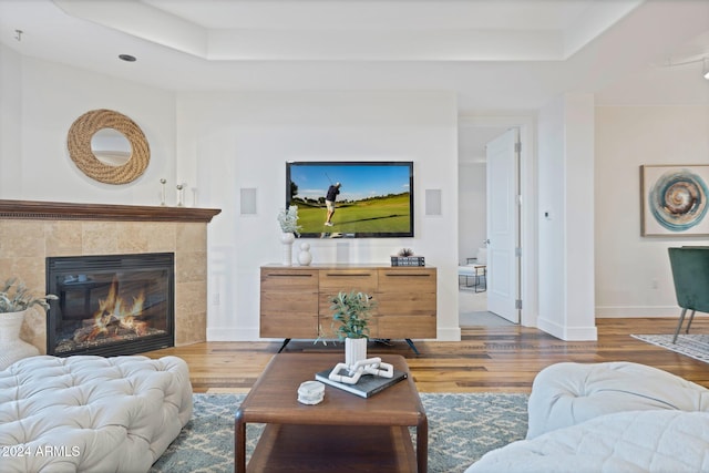 living room featuring a fireplace, hardwood / wood-style flooring, and a raised ceiling