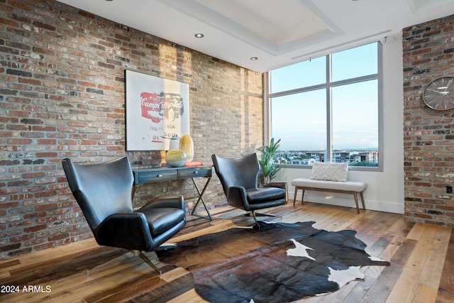 sitting room featuring hardwood / wood-style flooring, expansive windows, and brick wall