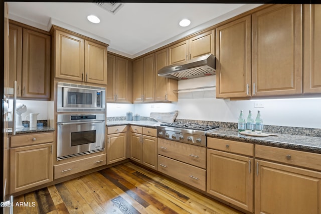 kitchen featuring stainless steel appliances, dark hardwood / wood-style floors, and dark stone counters