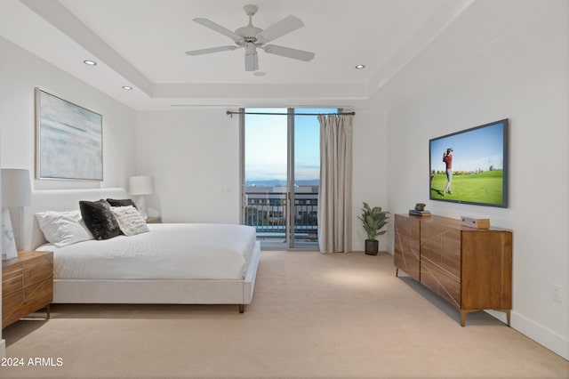 carpeted bedroom featuring access to outside, ceiling fan, and a tray ceiling