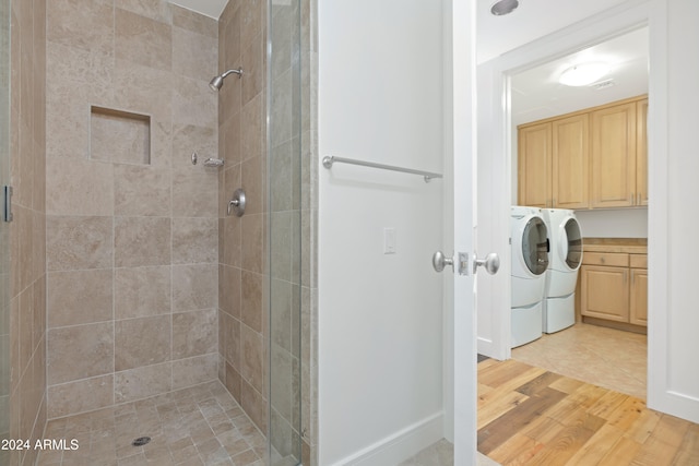 bathroom with hardwood / wood-style floors, a tile shower, and washing machine and clothes dryer