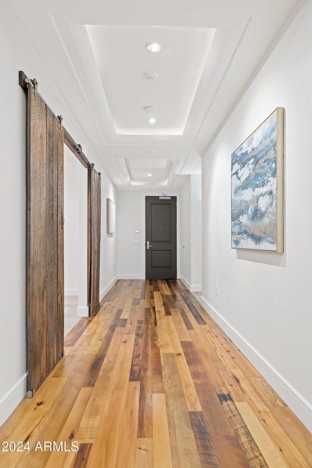 hallway featuring hardwood / wood-style floors, a barn door, and a raised ceiling