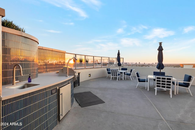 patio terrace at dusk featuring exterior kitchen and sink