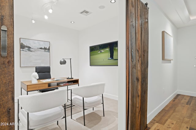 home office featuring light hardwood / wood-style floors and a barn door