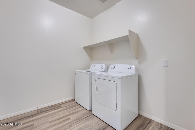 laundry area featuring light wood finished floors, laundry area, separate washer and dryer, and baseboards