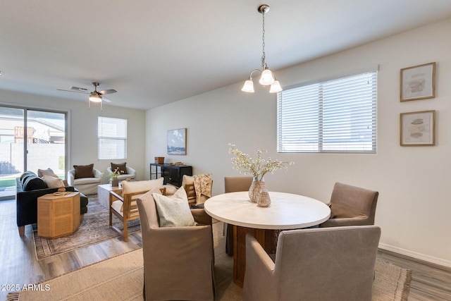 dining room with visible vents, baseboards, wood finished floors, and ceiling fan with notable chandelier