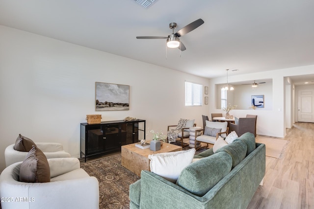 living area with visible vents, wood finished floors, and a ceiling fan