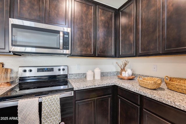 kitchen with stainless steel appliances, dark brown cabinetry, and light stone countertops