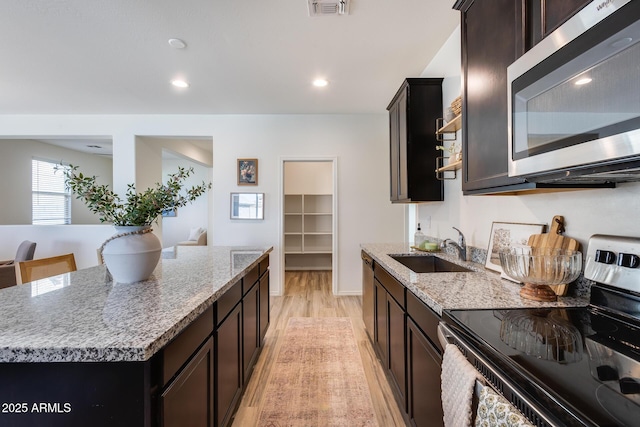 kitchen with stainless steel microwave, visible vents, light wood-style flooring, electric range oven, and a sink