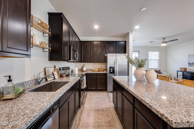 kitchen with light stone counters, appliances with stainless steel finishes, dark brown cabinets, open shelves, and a sink