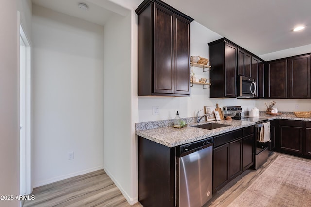 kitchen with light wood-style floors, appliances with stainless steel finishes, dark brown cabinets, and a sink