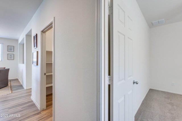 hall with visible vents, light wood-style flooring, and baseboards