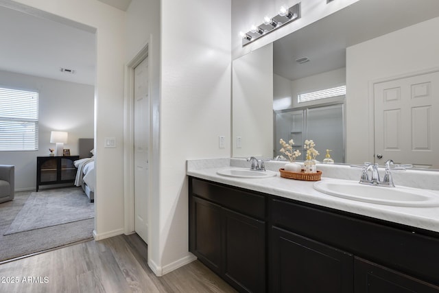 bathroom with double vanity, wood finished floors, a sink, and connected bathroom