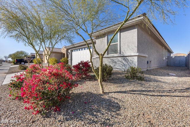 view of side of home featuring a garage, fence, and stucco siding