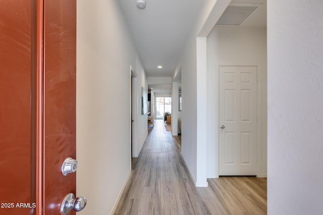 corridor with light wood-style floors, visible vents, and baseboards