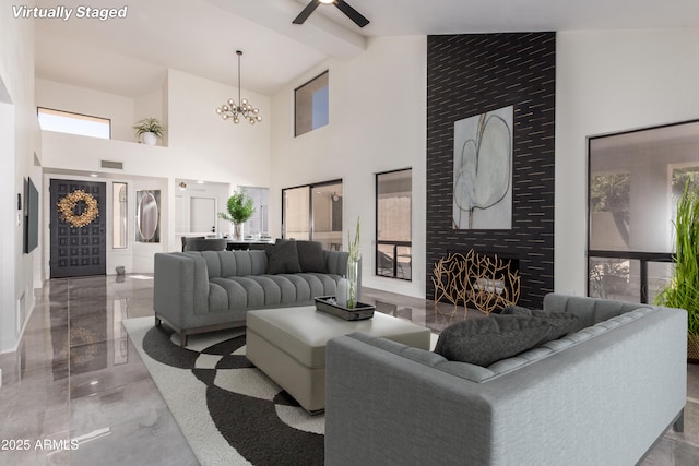 living room with a fireplace, beamed ceiling, high vaulted ceiling, and an inviting chandelier