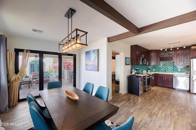 dining space featuring visible vents, beamed ceiling, and light wood-style flooring