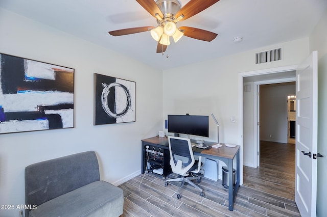 office area with wood tiled floor, visible vents, ceiling fan, and baseboards