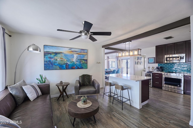 living area featuring dark wood-type flooring, a ceiling fan, visible vents, and baseboards