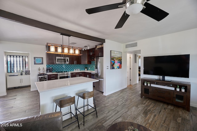 kitchen with stainless steel appliances, dark wood-style flooring, dark brown cabinets, light countertops, and backsplash