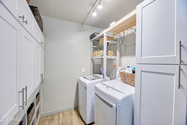 laundry area with light wood-style flooring, track lighting, washer and dryer, laundry area, and baseboards