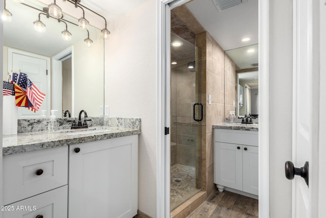 bathroom featuring hardwood / wood-style floors, vanity, and a shower with shower door