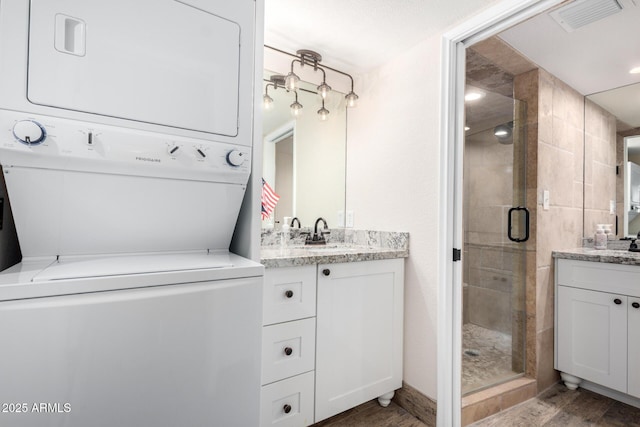 bathroom featuring stacked washer and dryer, vanity, wood-type flooring, and an enclosed shower